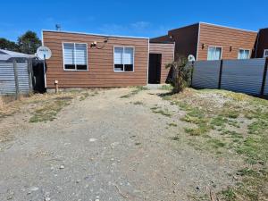 a house with a dirt yard in front of it at Cabaña ByB in Dalcahue