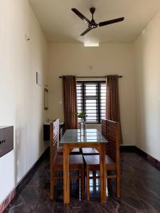 a dining room with a table and chairs and a ceiling fan at AP'S Homestay Nilambur in Nilambūr +4 photos