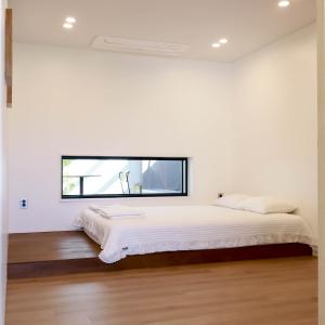 a white bedroom with a large bed and a window at Damonga in Damyang