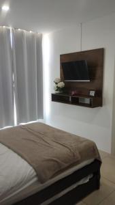 a bedroom with a bed and a flat screen tv at Camboriú Suites 307 in Salinas