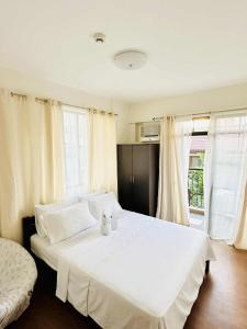 a bedroom with a large white bed and windows at THE PRECIOUS TIME LOUNGe in Davao City