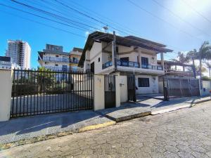 a white house with a gate in front of it at Sobrado 4 quartos com piscina praia do tabuleiro in Barra Velha