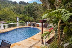 a swimming pool in a yard with a fence and trees at El Remanso del Colibri in La Vega