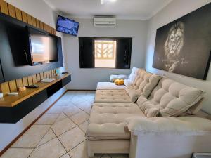 a living room with a couch and a flat screen tv at Sobrado 4 quartos com piscina praia do tabuleiro in Barra Velha