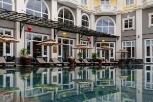 a hotel swimming pool with chairs and umbrellas at Hotel Royal Hoi An Danang, The Legacy Riverfront Resort & Spa in Hoi An