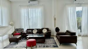 a living room with a leather couch and chairs at Beach Villas Phan Thiêt in Bình Sum