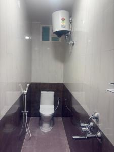 a bathroom with a toilet and a light on the wall at Eiffel Pondy in Pondicherry