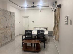 a bedroom with a bed and two chairs and a table at Eiffel Pondy in Pondicherry