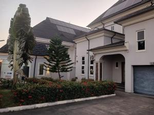 a white house with a palm tree and a garage at Premium 3 Bedroom Villa Upscale Alagbaka Area in Akure