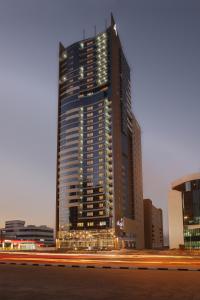 a tall building in a city at night at Nour Arjaan by Rotana-Fujairah in Fujairah