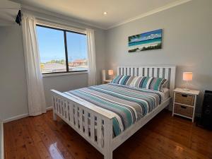 a white bedroom with a bed and a window at Callala Beach Shack - Pet Friendly in Callala Beach