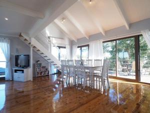 a dining room with a table and chairs and a television at Callala Beach Shack - Pet Friendly in Callala Beach