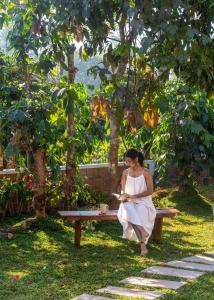a woman sitting on a bench reading a book at Kumberi Manor by Raho - Heritage Retreat in Coorg in Ammatti +47 photos