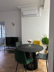 a dining room with a black table and green chairs at L Écrin d or in Montluçon