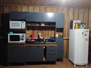 a kitchen with a sink and a microwave and a refrigerator at Casa da Duda in São Gabriel
