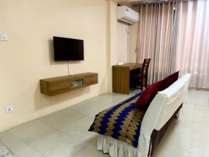 a living room with a couch and a tv on the wall at The Abode in Kathmandu