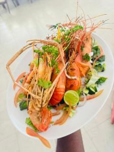a plate of shrimp and vegetables on a white plate at Open Sky Villa in Hikkaduwa