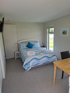 a bedroom with a bed and a table and a window at Time n Tide in Athenree