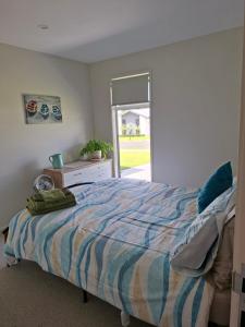 a bedroom with a bed and a dresser and a window at Time n Tide in Athenree +7 photos