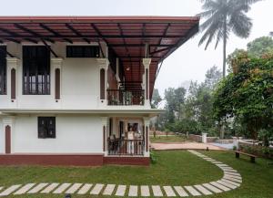 two people standing on the balcony of a building at Kumberi Manor by Raho - Heritage Retreat in Coorg in Ammatti