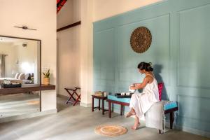 a woman sitting on a chair in a room at Kumberi Manor by Raho - Heritage Retreat in Coorg in Ammatti