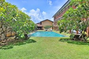 a swimming pool in a yard next to a building at The Long Beach Resort & Spa in Koggala