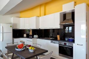 a kitchen with white cabinets and a table with fruit on it at Helion Apartments - Parallel in Gouvia