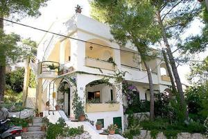 una gran casa blanca con árboles delante de ella en Apartments Grbesa, en Trogir