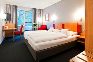 a hotel room with a large bed and red chairs at Ringhotel Ahrensburg in Ahrensburg