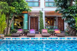 a resort with a swimming pool and chairs and a building at Villa Sirilanna Hotel in Chiang Mai