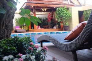 a swimming pool with a chair next to some plants at Villa Sirilanna Hotel in Chiang Mai