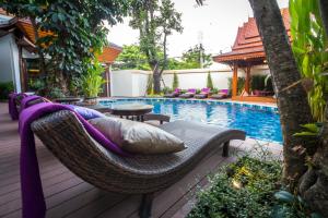 a wicker chair sitting on a deck next to a swimming pool at Villa Sirilanna Hotel in Chiang Mai