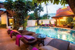 a swimming pool with wicker chairs and a table at Villa Sirilanna Hotel in Chiang Mai
