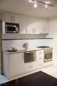 a kitchen with white cabinets and a sink and a microwave at Arlberg Hotham in Mount Hotham