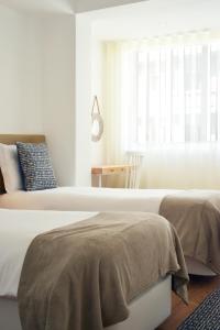 2 camas en una habitación blanca con ventana en Spot Apartments Ceuta, en Oporto