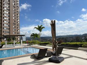 a pool with two chairs and a umbrella on a building at Avida Aspira Tower 1 - Chads Unit 8th Floor in Cagayan de Oro