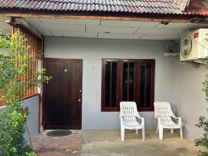 two white chairs sitting outside of a house at Friend Guesthouse , Kho Lanta in Ko Klang