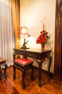 a desk with a lamp and a vase of flowers on it at Villa Sirilanna Hotel in Chiang Mai