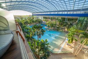 ein Einkaufszentrum im Innenbereich mit einem Pool und Palmen in der Unterkunft Hotel Victory Therme Erding in Erding