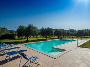 a swimming pool with chairs and trees in the background at Il Piratello - Agriturismo Baldeschi in Tuoro sul Trasimeno