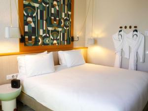 a bedroom with a white bed and clothes hanging on a wall at Mercure Vichy in Vichy +38 photos