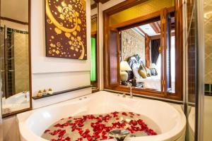 a bath tub filled with red flowers in a bathroom at Villa Sirilanna Hotel in Chiang Mai
