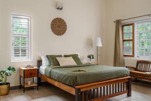 a bedroom with a large bed and two windows at Chetty's Mane by Raho - Estate-View Heritage Stay in Siddapur +47 photos