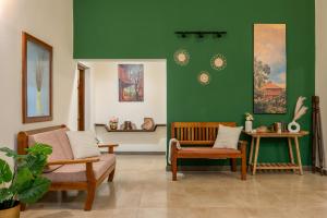 a living room with two chairs and a green wall at Chetty's Mane by Raho - Estate-View Heritage Stay in Siddapur