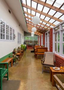 a restaurant with wooden tables and benches and windows at Chetty's Mane by Raho - Estate-View Heritage Stay in Siddapur