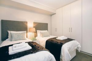 a bedroom with two beds with towels on them at Superior Apartment Mayfair in Cape Town