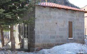 un piccolo edificio in pietra con una porta e un albero di Shushanik Home a Jermuk