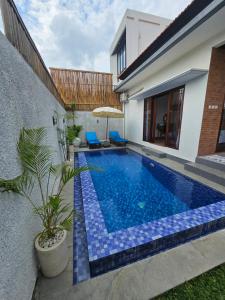 a swimming pool with blue tiles on the side of a house at Villa Casa Delta Canggu in Canggu