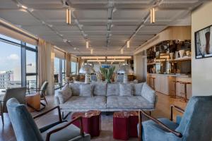 a living room with a large white couch and chairs at Publica Isrotel, Autograph Collection in Herzliya +60 photos