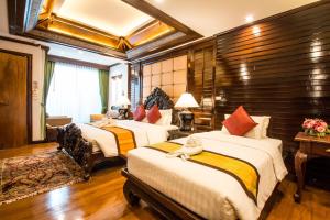 a hotel room with four beds in a room at Villa Sirilanna Hotel in Chiang Mai